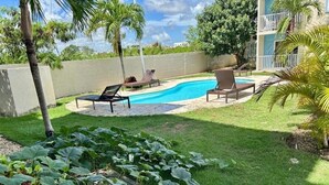 Ein Garten mit Swimmingpool, Liegestühlen und einem gepflegten Rasen.