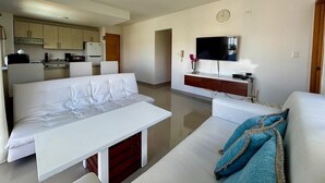 Ein modernes Wohnzimmer mit einer Couch, einem Couchtisch und einem an der Wand befestigten Fernseher.