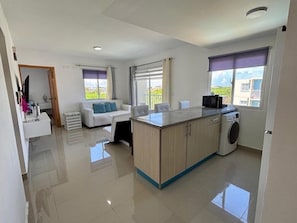 A modern apartment with a kitchen, a living area with a sofa, and a balcony. - Luxury Punta Cana Retreat - Gated Community - Fast Wi-Fi (Punta Cana)