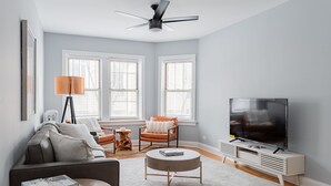 Un salon moderne avec un canapé, un fauteuil, une table basse et un téléviseur.