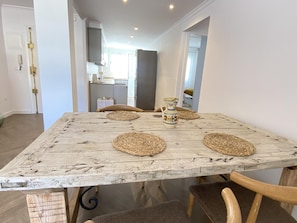 A dining area with a rustic wooden table, woven placemats, and a decorative pitcher.