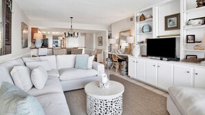 A modern living room with a sectional sofa, a coffee table, and a flat-screen TV.