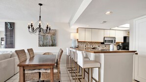 A modern kitchen with a central island, white cabinetry, and a chandelier.