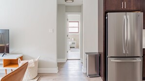 A modern kitchen with a stainless steel refrigerator, wooden cabinets, and a white countertop. - Modern Aesthetic 2BR in Evanston Near the Beach (Evanston)