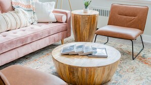 A modern living room with a pink sofa, a round wooden coffee table, and a brown leather armchair. - Modern Aesthetic 2BR in Evanston Near the Beach (Evanston)