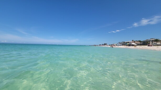 A beach with clear turquoise water and a few buildings in the background. - Bradenton Beach/Anna Maria Island, IMG Academy, Longboat Key, Sarasota (Bradenton)