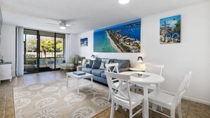 A spacious living room with a large window, a sofa, a coffee table, and a dining area with chairs and a table. - Bradenton Beach/Anna Maria Island, IMG Academy, Longboat Key, Sarasota (Bradenton)