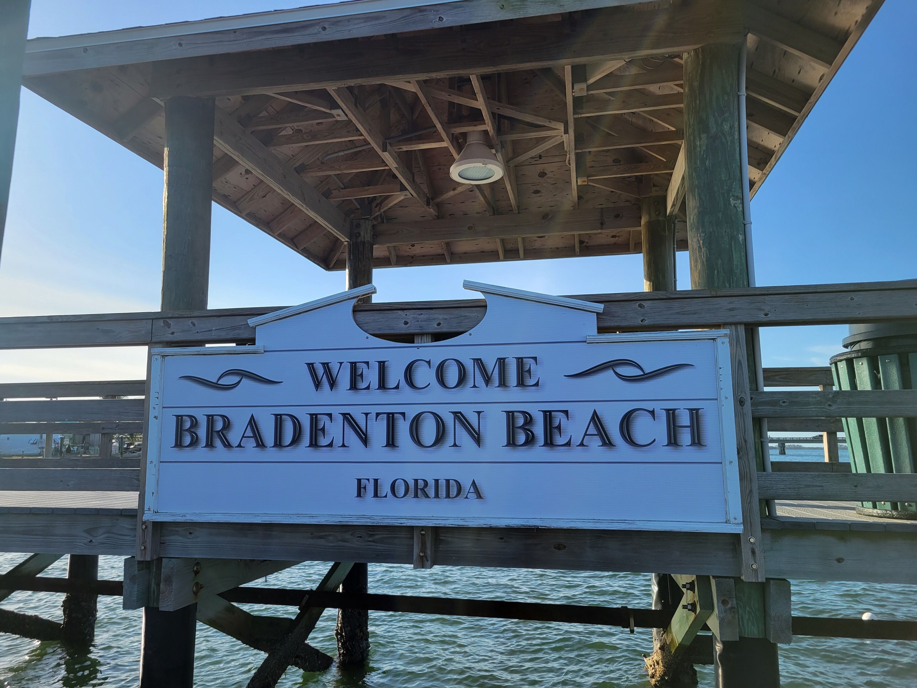 Un letrero de madera con la inscripción 'WELCOME BRADENTON BEACH FLORIDA'.
