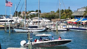 A marina with multiple boats docked, a flag, and a building with a sign. - Bradenton Beach/Anna Maria Island, IMG Academy, Longboat Key, Sarasota (Bradenton)