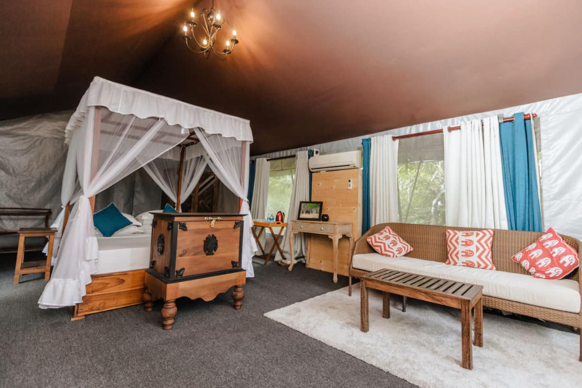 Een knus ingerichte kamer met een hemelbed, een houten dressoir, een rieten bank en een bureau met stoel.