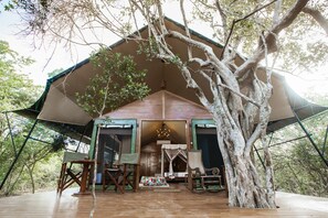 A treehouse with a wooden deck, a bed, and a dining area. - Tribe Yala - Luxury Camping (Thissamaharama)