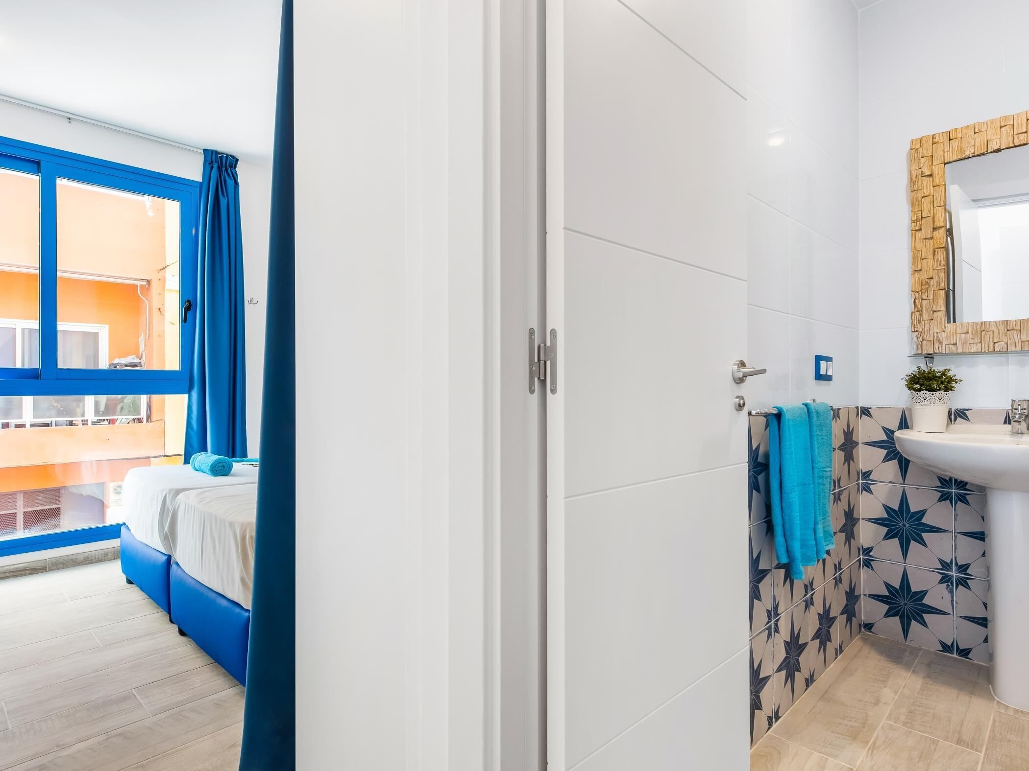 Habitación de hotel con cama, baño con lavamanos y espejo, y vistas al exterior.
