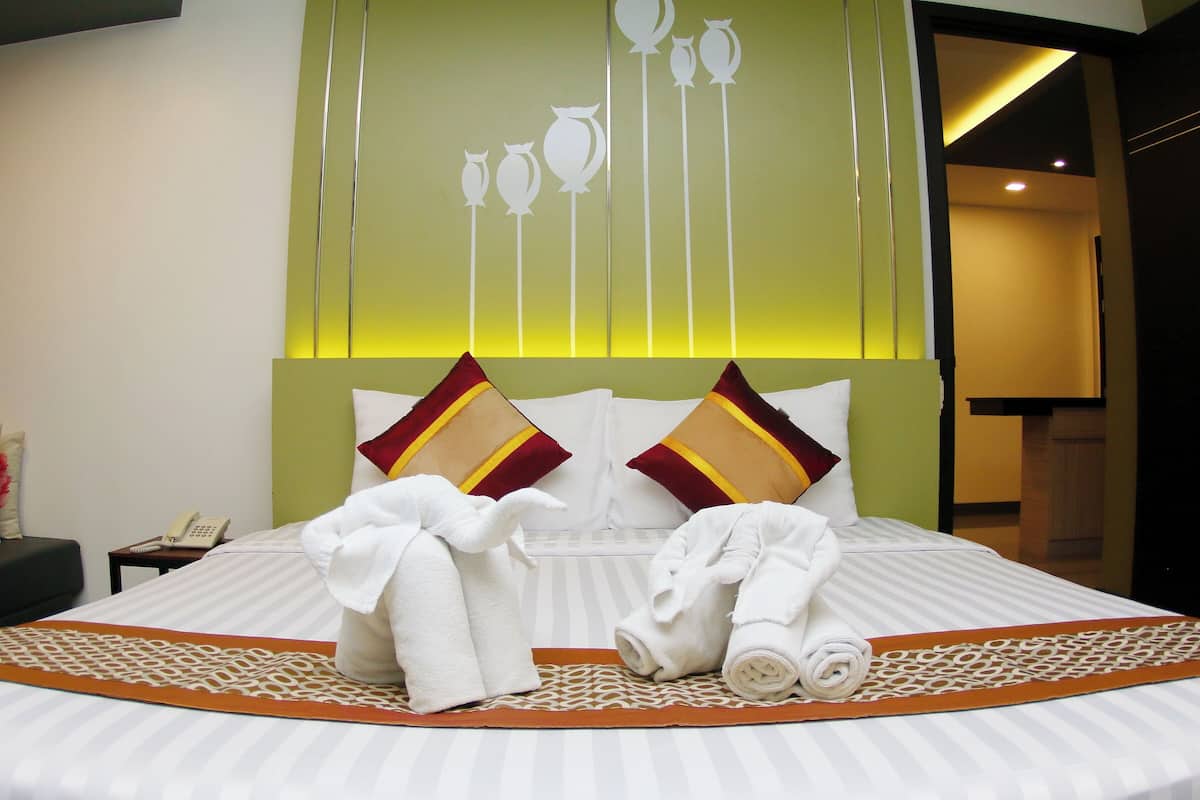 A hotel room with a neatly made bed, a bedside phone, and a decorative wall panel.