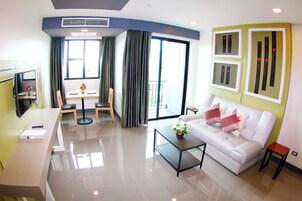 Una sala de estar moderna con un sofá blanco, una mesa de centro, un televisor y un comedor con mesa y sillas.