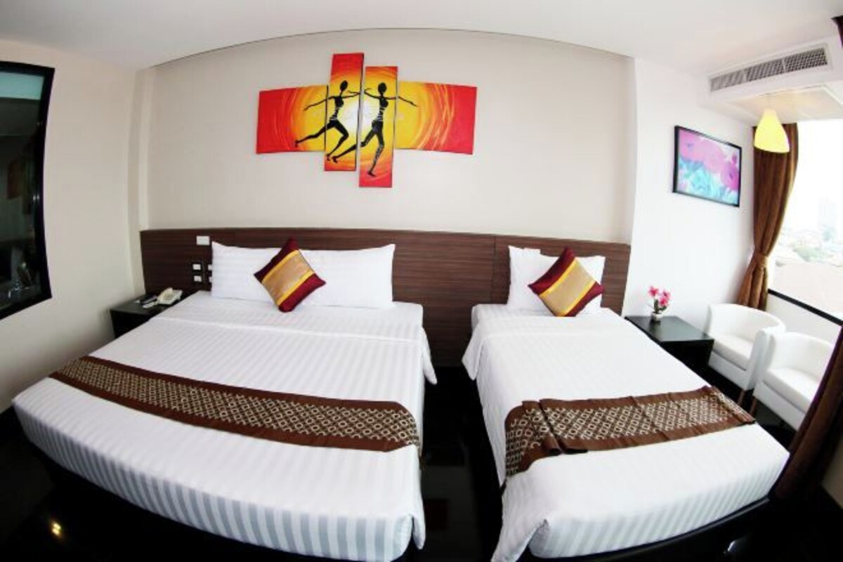 Ein Hotelzimmer mit zwei Betten, einem großen Kunstwerk an der Wand, einem Schreibtisch mit Lampe und einem Sessel.