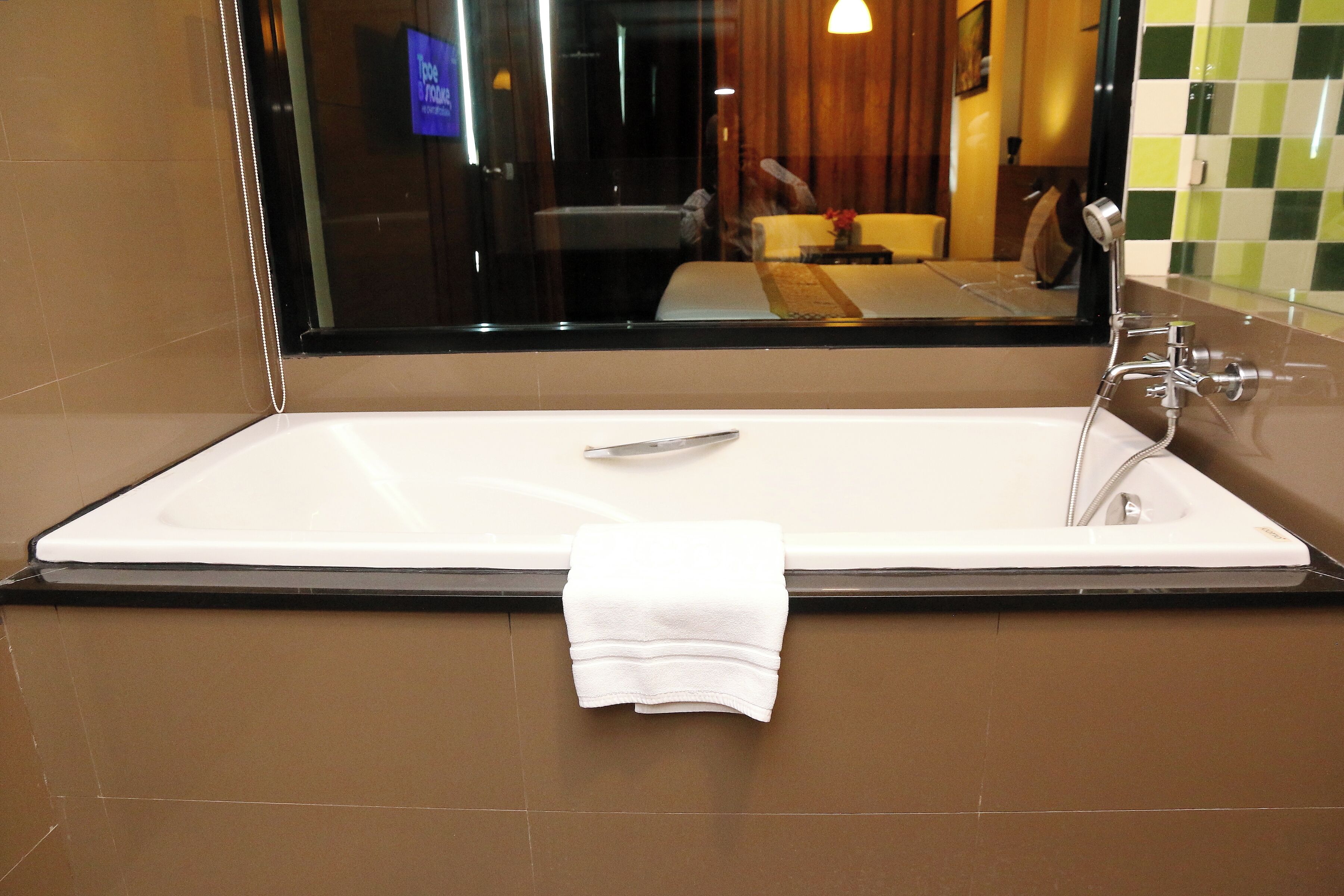 Une salle de bain moderne avec une grande baignoire, un miroir et une serviette accrochée au mur.