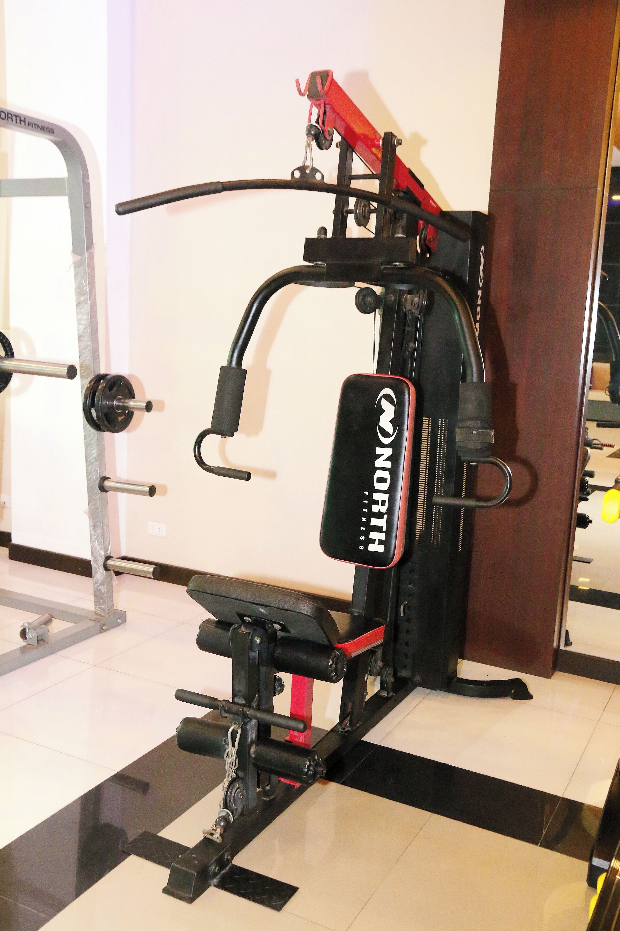 A gym with a weightlifting machine labeled "NORTH FITNESS".