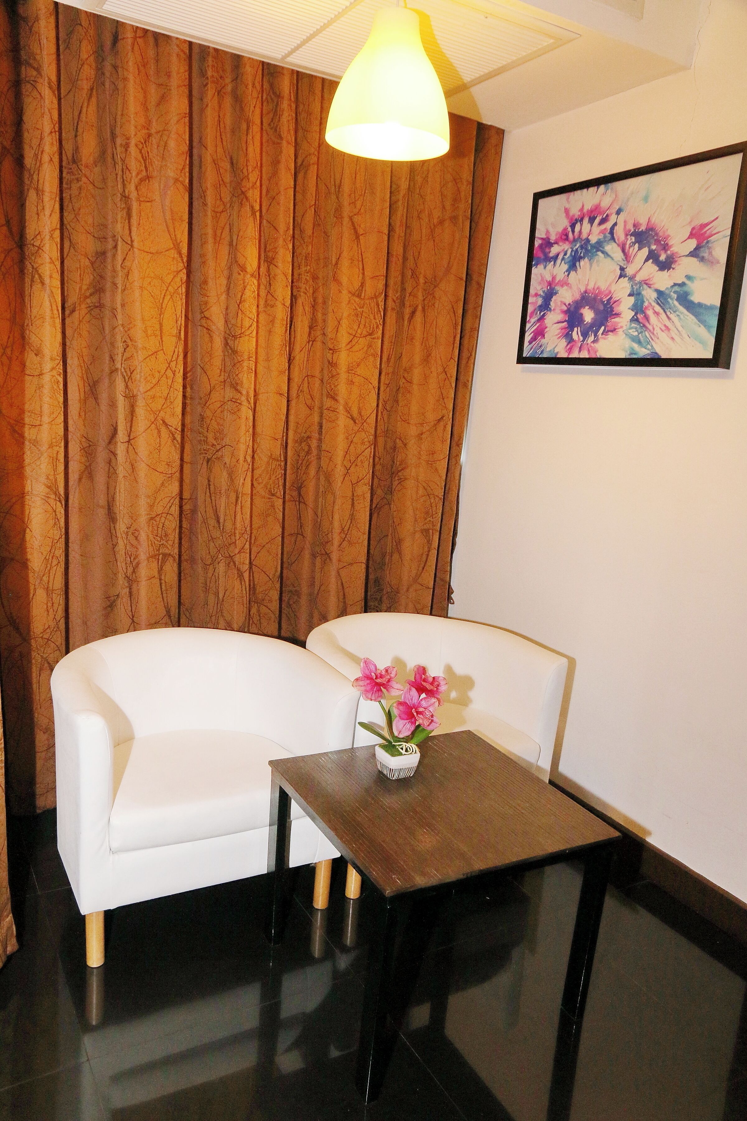 A room with a white sofa, a small wooden table with a vase of flowers, and a wooden panel wall.