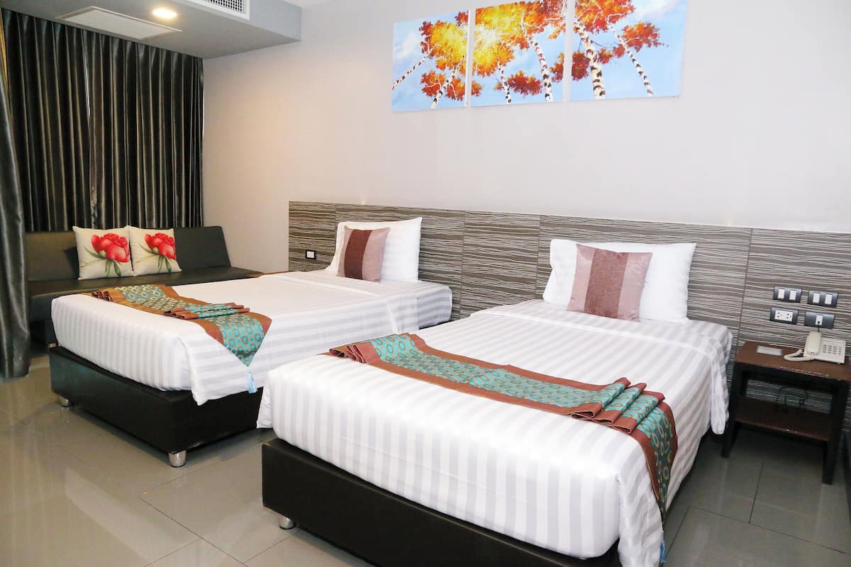 A hotel room with two beds, a sofa, a nightstand with a phone, and a painting on the wall.