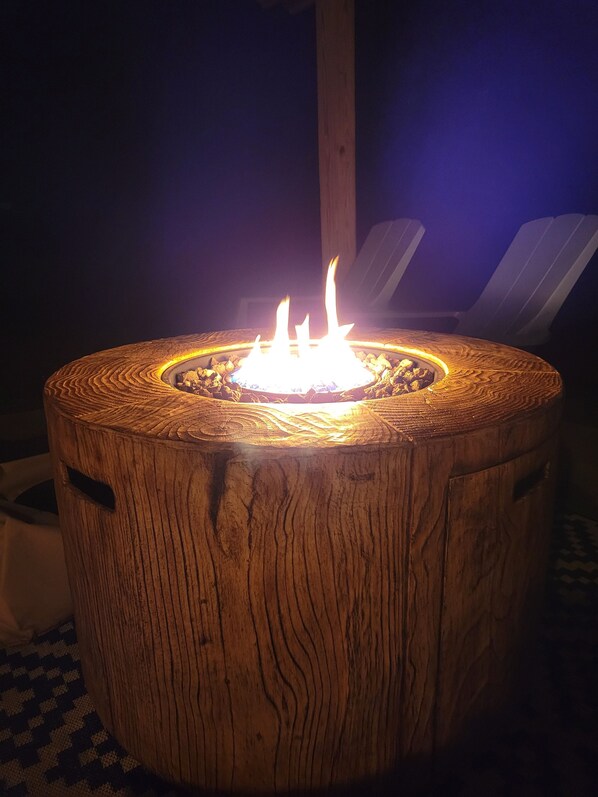 A wooden fire pit with a circular design and a central flame.