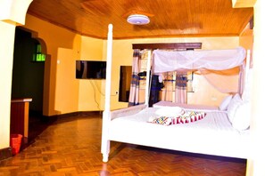 A room with a bed, a television, and a wooden ceiling.