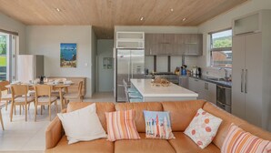 Een moderne keuken met roestvrijstalen apparatuur, een eethoek met tafel en stoelen, en een woonkamer met een bank en kussens.