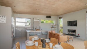 Een moderne keuken met een eethoek, een aan de muur bevestigde televisie en een open haard.