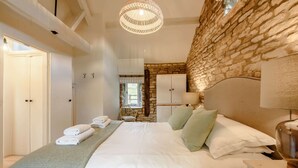 Un dormitorio con una cama grande, pared de piedra y una lámpara colgante.