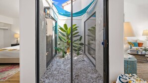 A hotel room with a sliding glass door leading to a balcony with plants and a blue cloth. - Modern Chic Condo at Rancho Las Palmas (Rancho Mirage)