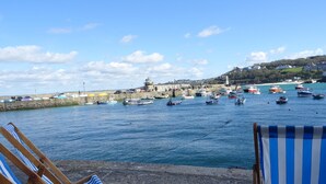 Un port amb vaixells, un far i una paret de pedra. Hi ha gandules a franxes al primer pla.