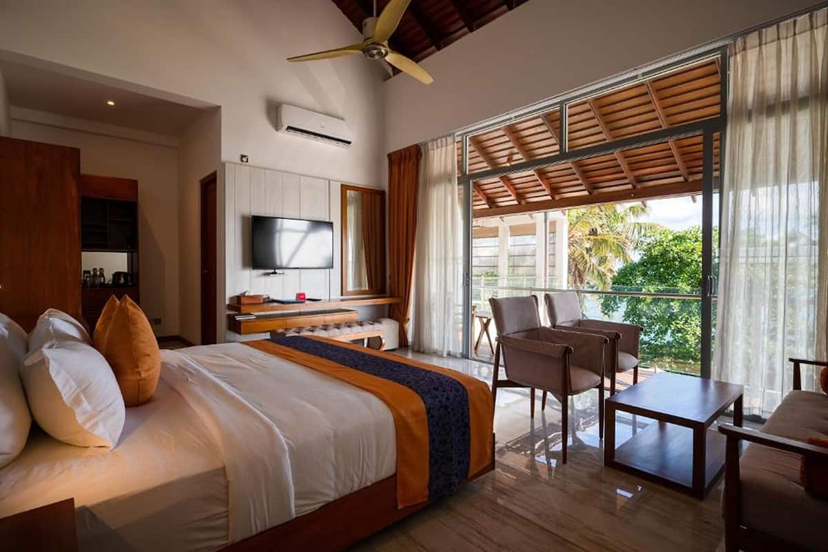 Une chambre d’hôtel avec un lit, une télévision, un bureau et un balcon offrant une vue.