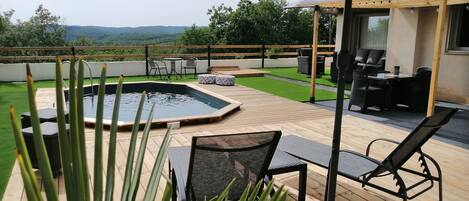 A rooftop patio with a swimming pool, outdoor furniture, and a view of the landscape.