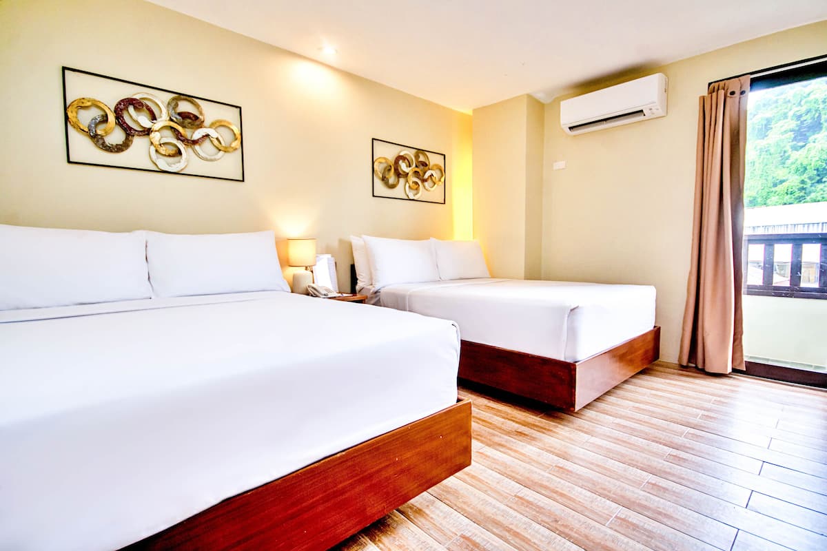 A hotel room with two beds, wooden flooring, and artwork on the walls.
