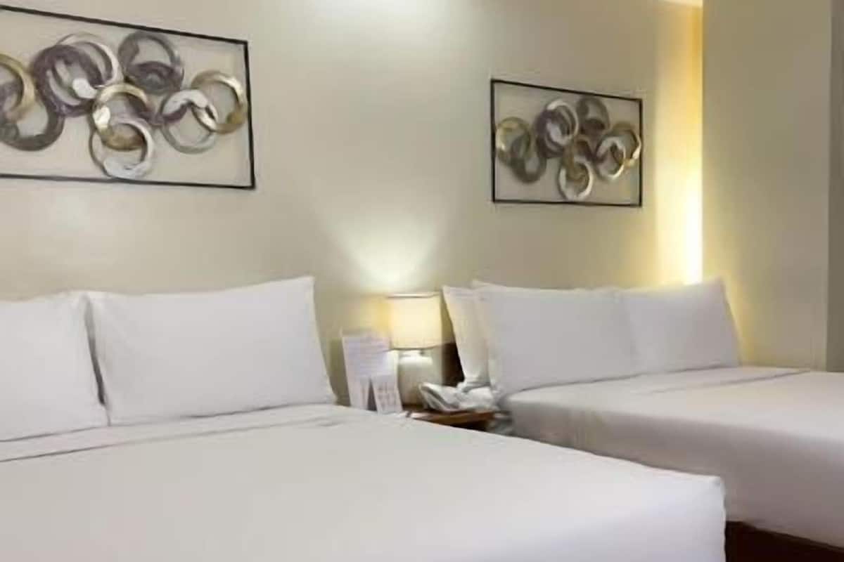 A hotel room with two beds, a nightstand, and abstract wall art.