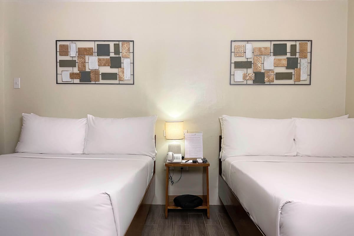 A hotel room with two beds, a nightstand with a lamp, a phone, and a sign.