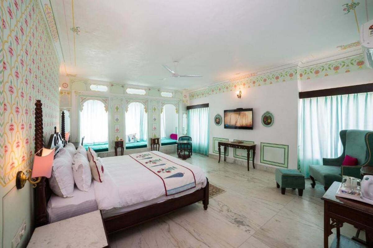A hotel room with a bed, a sitting area with a chair, a table, and a television.