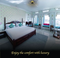 A spacious bedroom with a large bed, a vanity, and a view of the city.