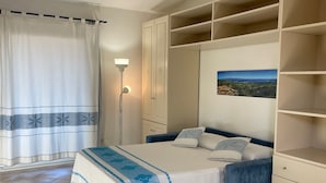 Une chambre à coucher avec un lit, une table de chevet, une armoire et une fenêtre avec un rideau.