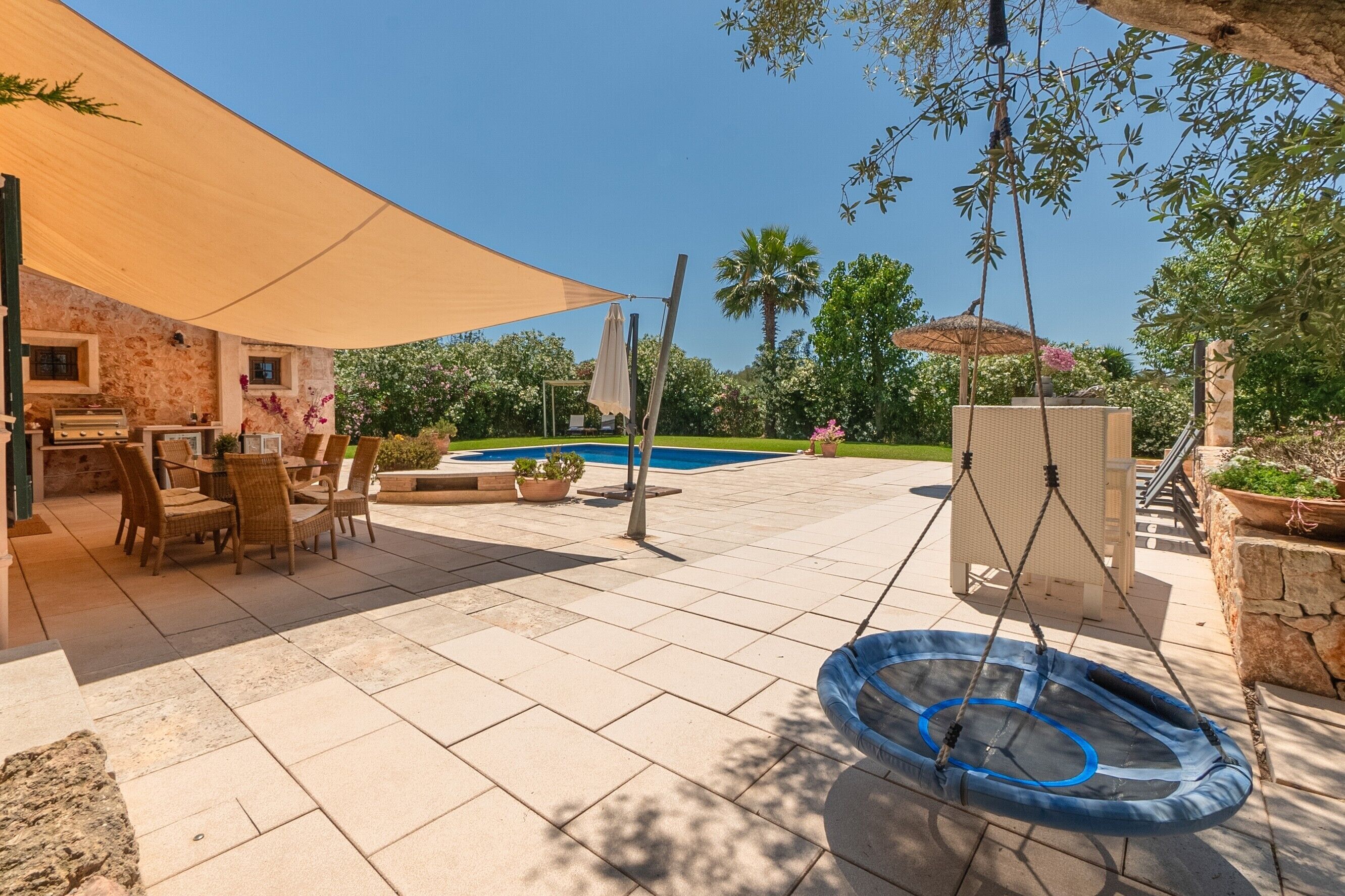 Un patio con piscina, mobiliario exterior y un columpio.