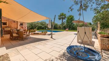 Un patio con piscina, mobiliario exterior y un columpio.