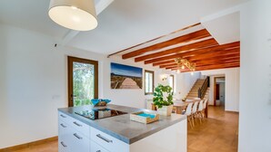 A modern kitchen with a central island, white cabinets, and a wooden ceiling. - Country House Finca Kiana with Pool, Garden & Wi-Fi (Sencelles)