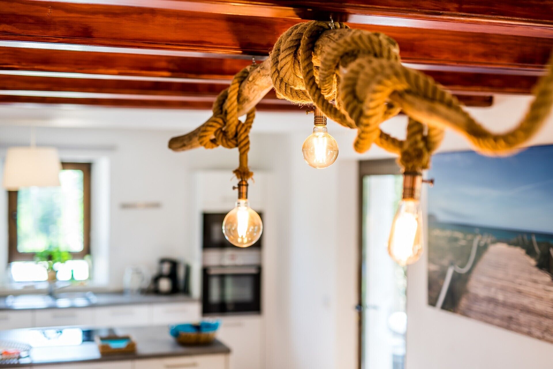 Una cocina con vigas de madera, lámparas colgantes y vistas al exterior.
