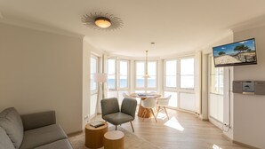 A modern living room with a sofa, a chair, a round table, and a TV mounted on the wall. - Dünenresidenz, App. A14 (Heringsdorf)