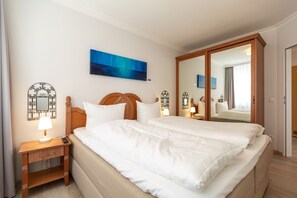 Ein Hotelzimmer mit Bett, Nachttisch, Lampe und einem großen Spiegel.
