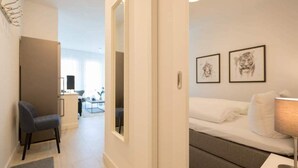 Una camera d'albergo moderna con un letto, una scrivania e una sedia. Alle pareti ci sono quadri incorniciati e una lampada sul comodino.