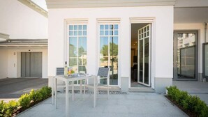 Un edificio moderno con un patio attrezzato con tavolo e sedie, ampie finestre e un ingresso.