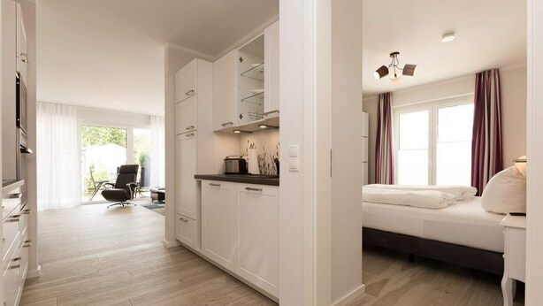 A modern hotel room with a bed, a desk, and a kitchenette. - Villa Strandgrün, App. 04 (Heringsdorf)