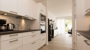 A modern kitchen with white cabinets, stainless steel appliances, and a wooden countertop. - Villa Strandgrün, App. 04 (Heringsdorf)