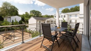 A balcony with a table and chairs, overlooking a residential area with houses and greenery. - Villa Strandgrün, App. 04 (Heringsdorf)