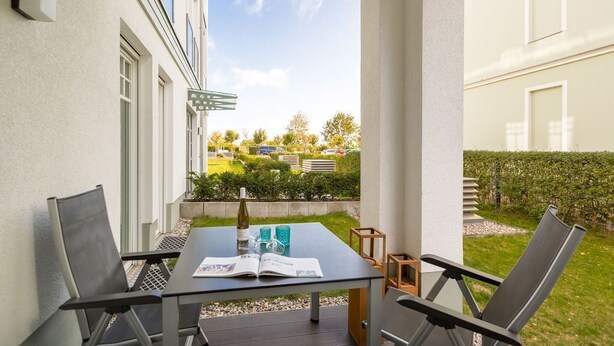Un balcon avec une table, des chaises et une bouteille de vin.